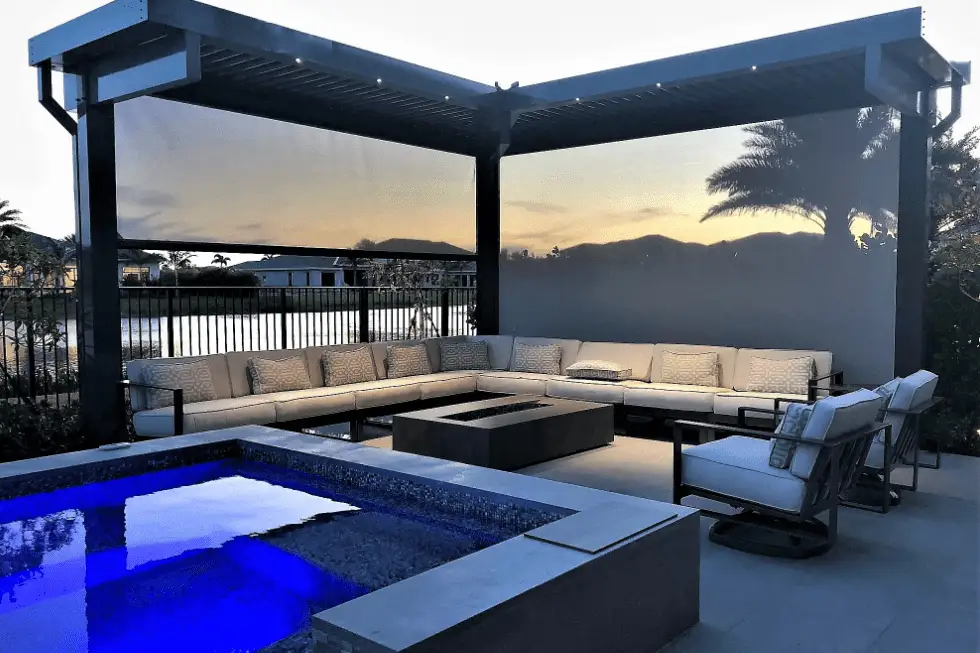 Poolside pergola with motorized outdoor screens creating a private, shaded outdoor living space at dusk